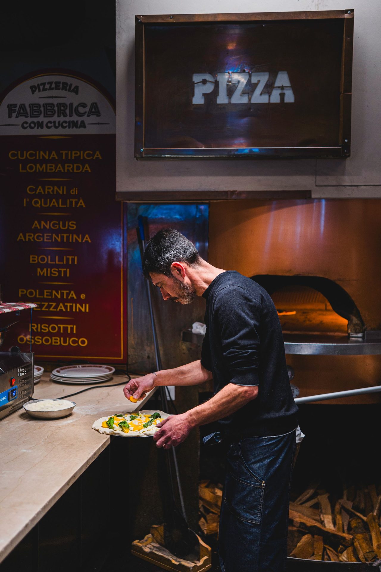 Il banco pizza di Fabbrica con l'insegna rossa PIZZA e il forno