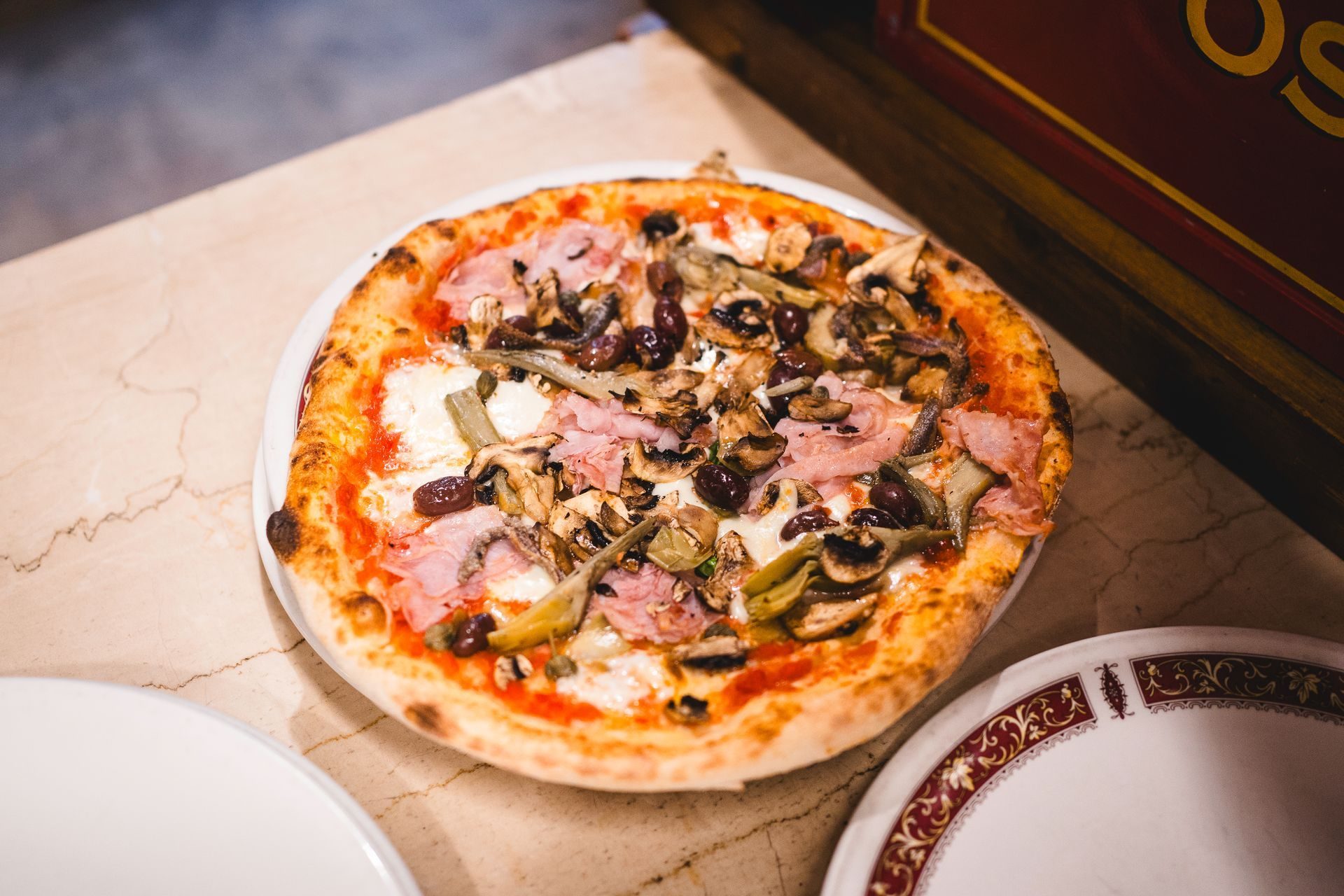 Pizza capricciosa con funghi, prosciutto e carciofi